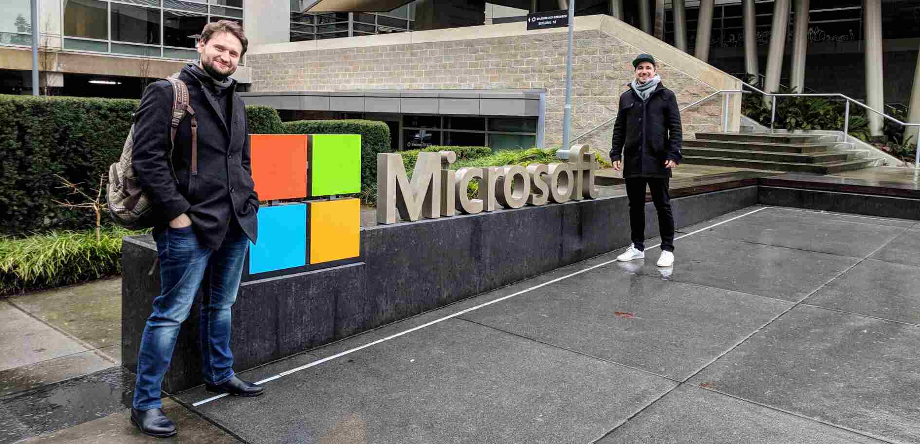 Foto von zwei Mitarbeitern vor dem Microsoft Logo in Redmond