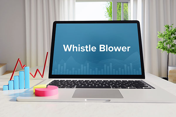 Notebook auf Schreibtisch mit Schriftzug "Whistleblower" und Grafik